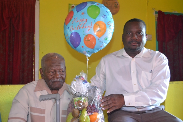 Butlers Villager Mr. William Douglas celebrating his 101 birthday is presented with a fruit basket from Permanent Secretary in the Ministry of Social Development Keith Glasgow on behalf of the Ministry at his home in Butlers Village on October 08, 2015